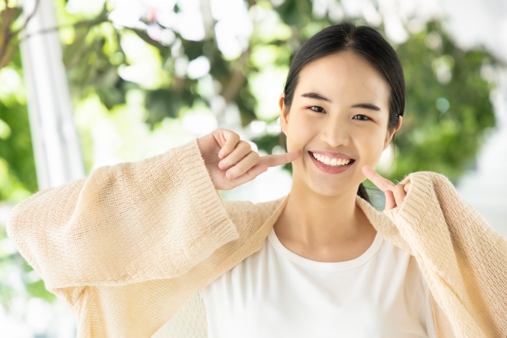 Happy,Smiling,Asian,Woman,In,Casual,Dress,,Smiling,While,Showing 1766172059 shutterstock 2443565077 1