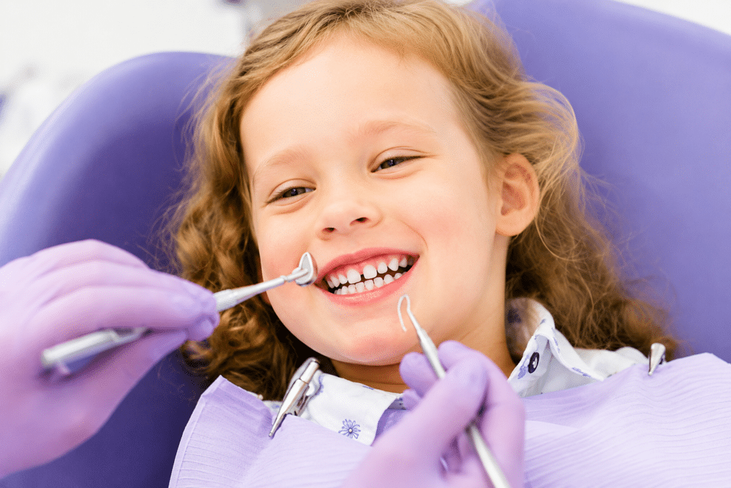 Close-up of a smiling little girl getting her teeth cleaned as part of a regularly schedule dental cleaning and exam.