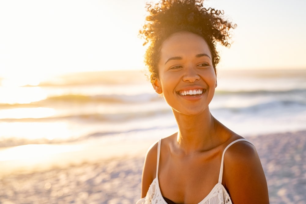 Woman standing outdoors and showing off her bright smile after all-on-4 dental implants for full mouth restoration.